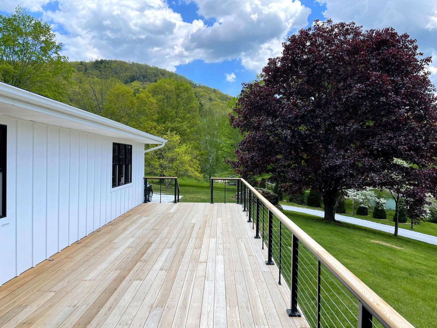 Cedar deck with black cable railing looking out over trees and hills