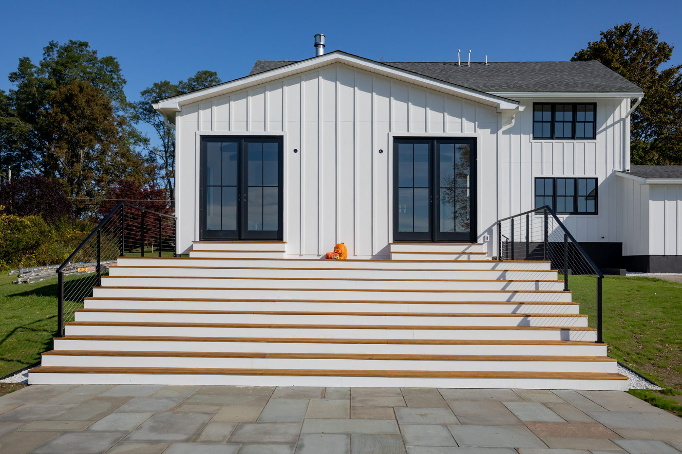 White modern farmhouse with black-framed windows above a bluestone stair