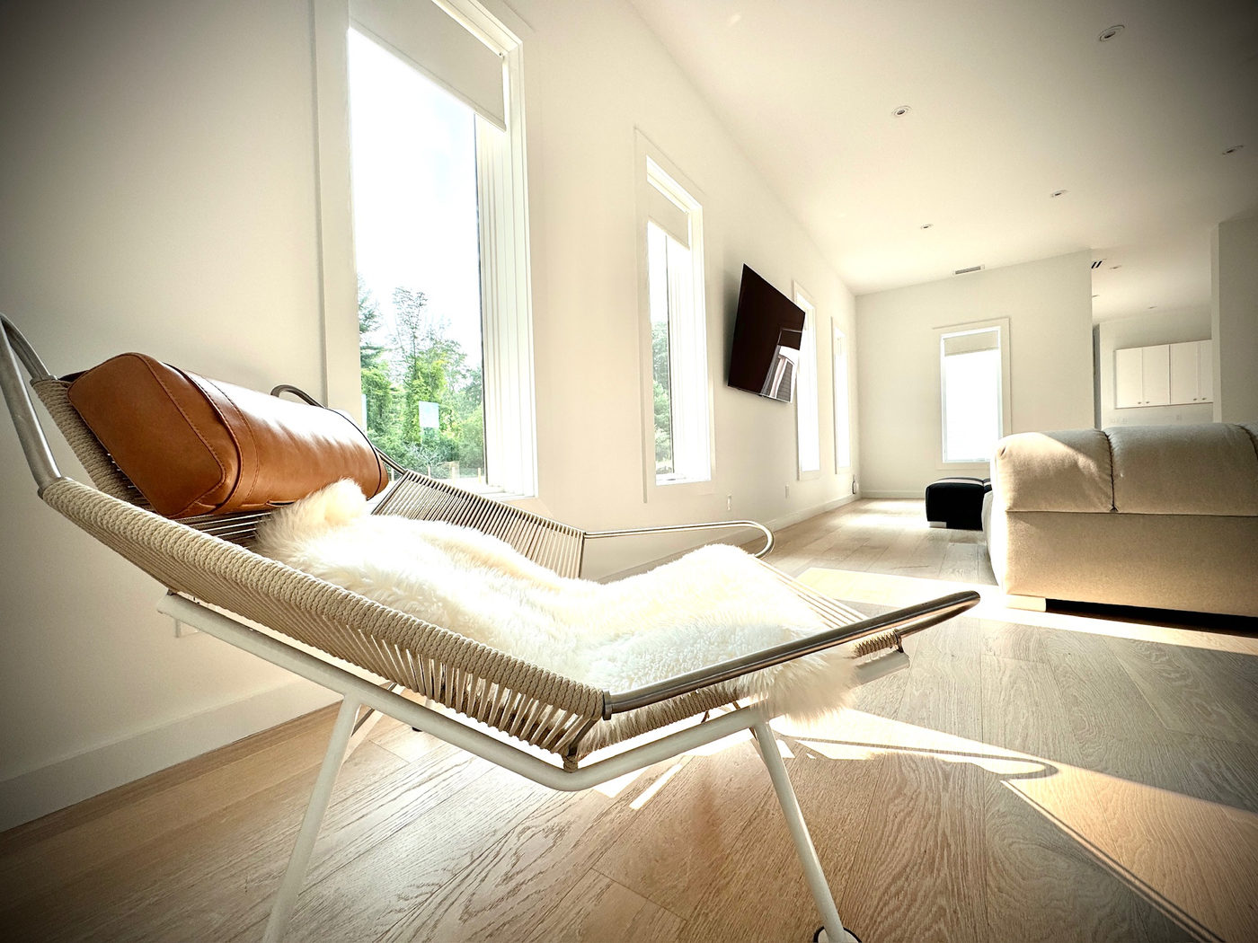 Living room with a leather-and-chrome lounge chair and pale oak floors