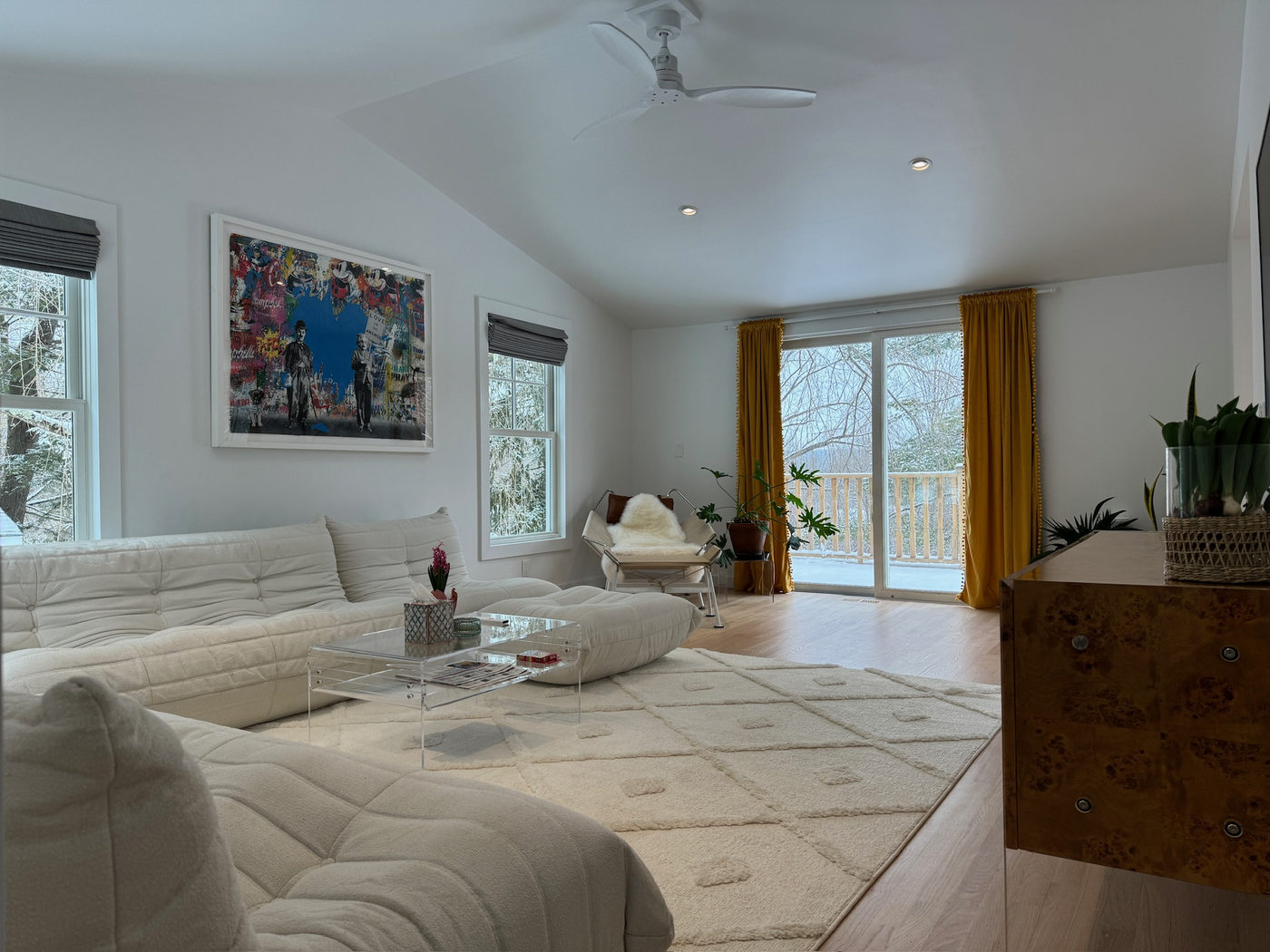 Living room with a large white sectional, sliding doors and gold curtains
