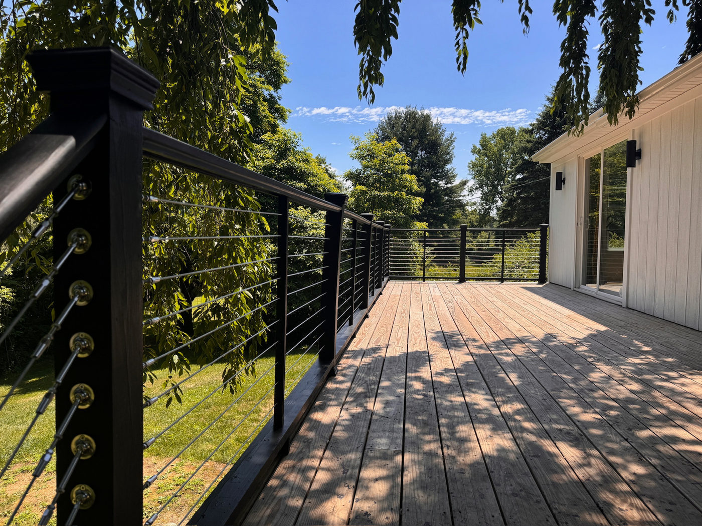 Wood deck with black cable railing looking into the trees