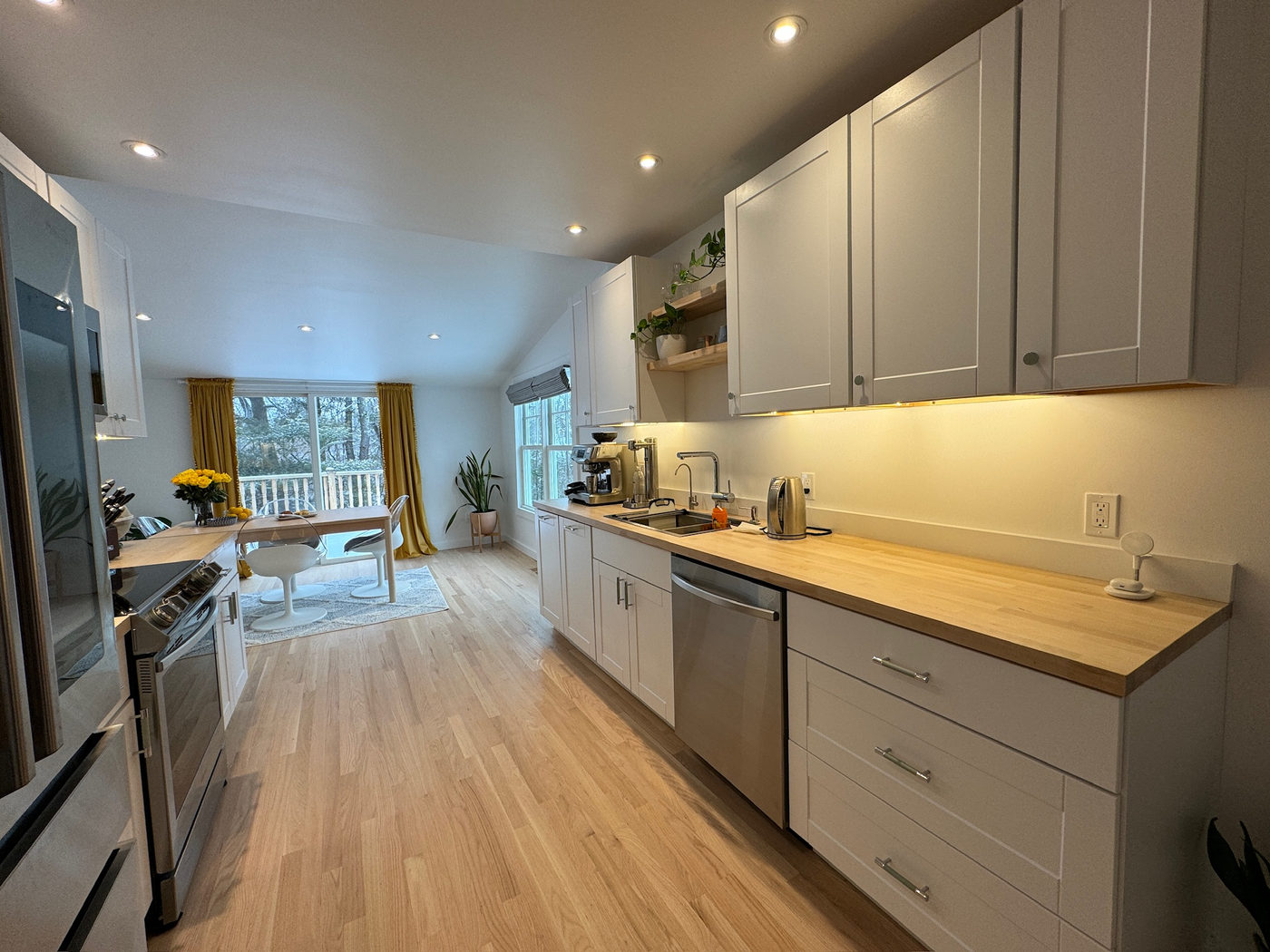 Kitchen with white shaker cabinets, wood counter and stainless range