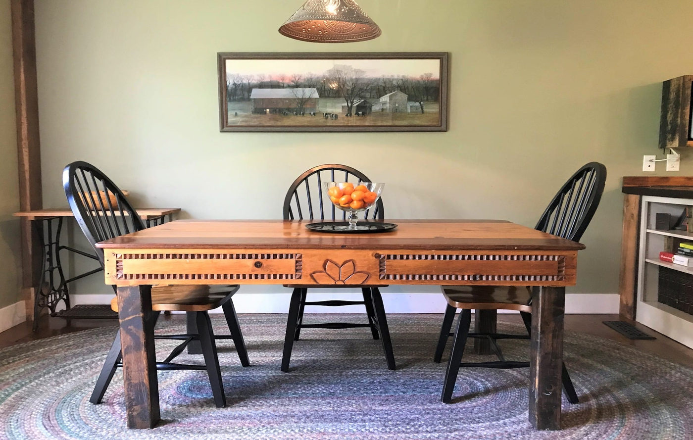 Dining room with a wooden table, spindle-back chairs and a framed landscape
