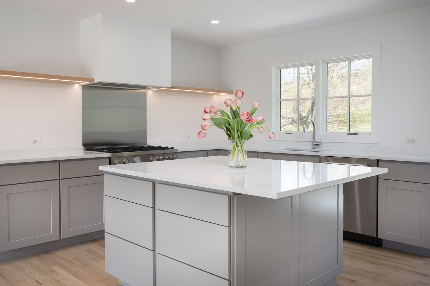 White kitchen with a marble island, gas range and fresh flowers