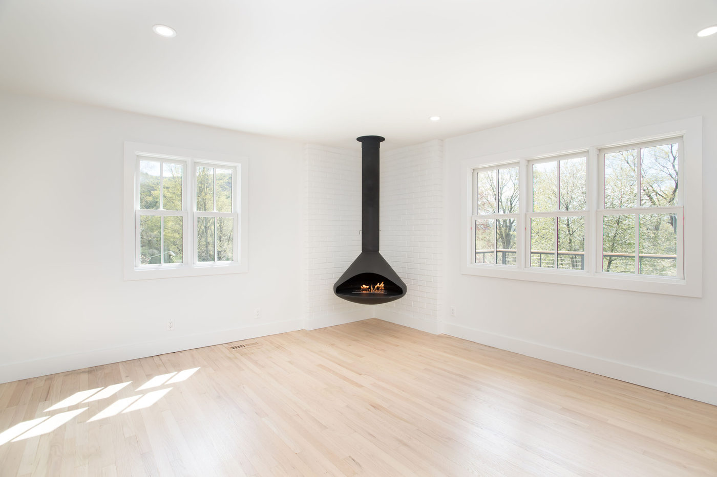 Open living room with a black wood stove and pale oak floors