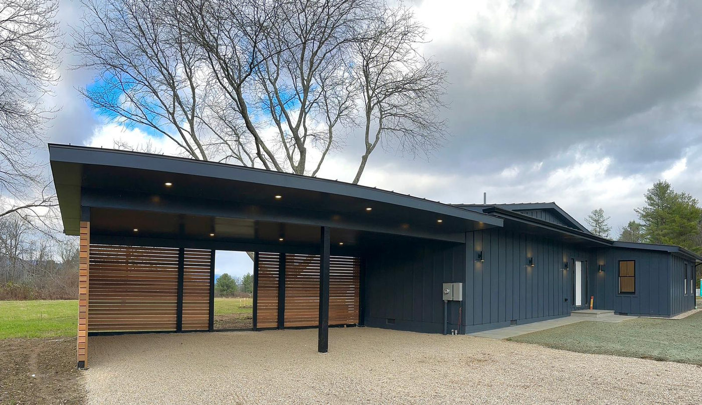 Low mid-century house with dark vertical siding and a deep overhanging roof