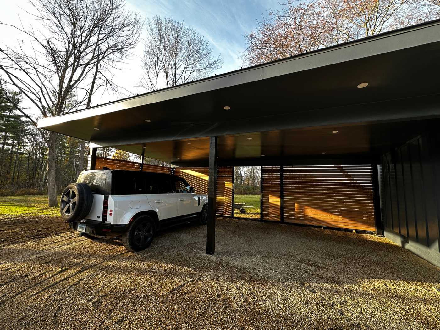 Open carport beneath the deep roof line of the mid-century house