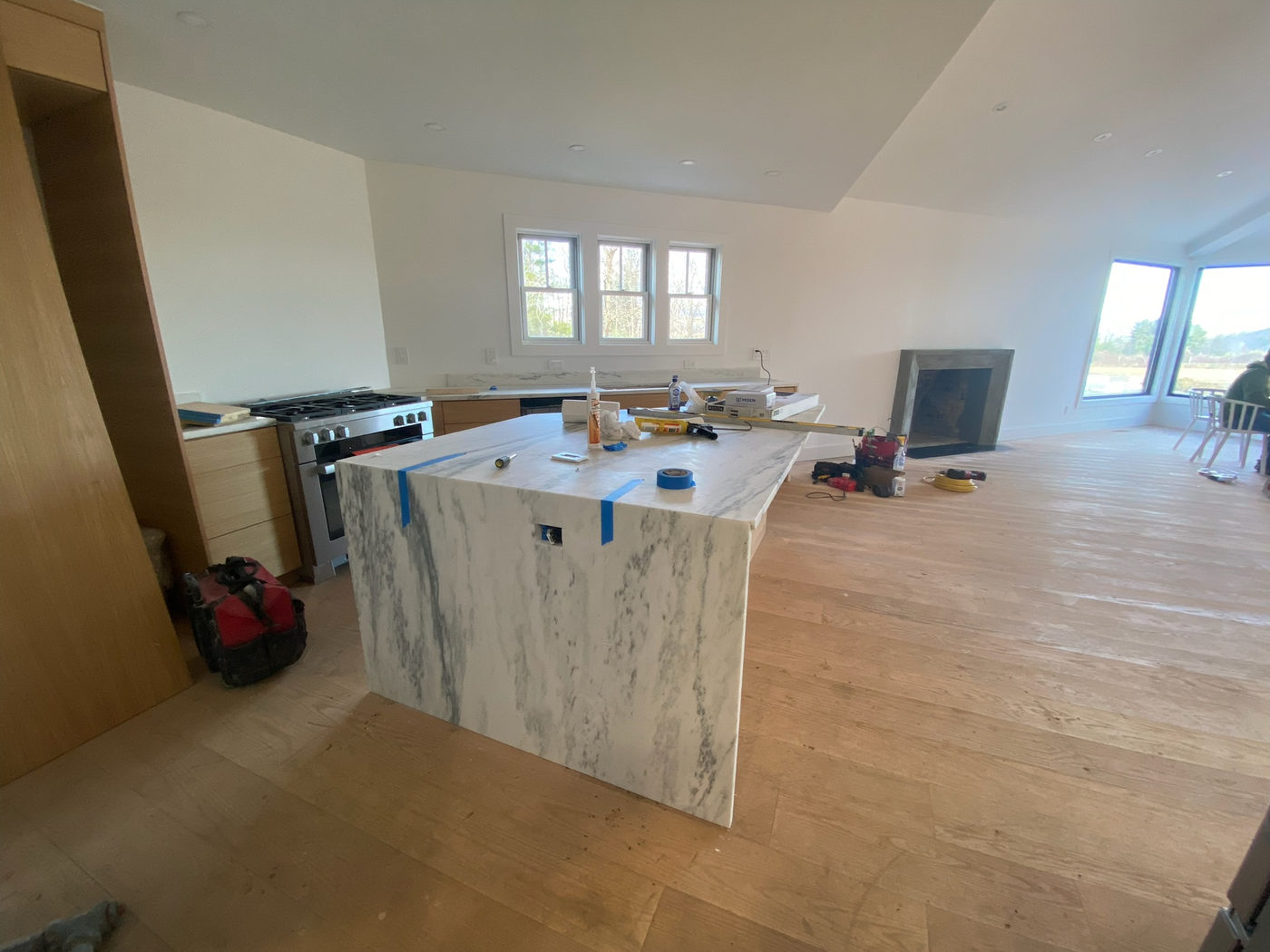 Kitchen under construction with a stone waterfall island and new range