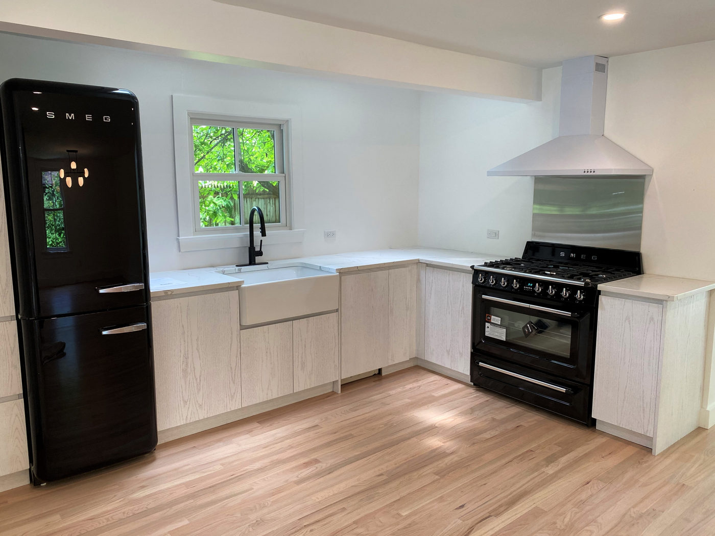 Kitchen with custom white oak cabinets, a black range and a farmhouse sink