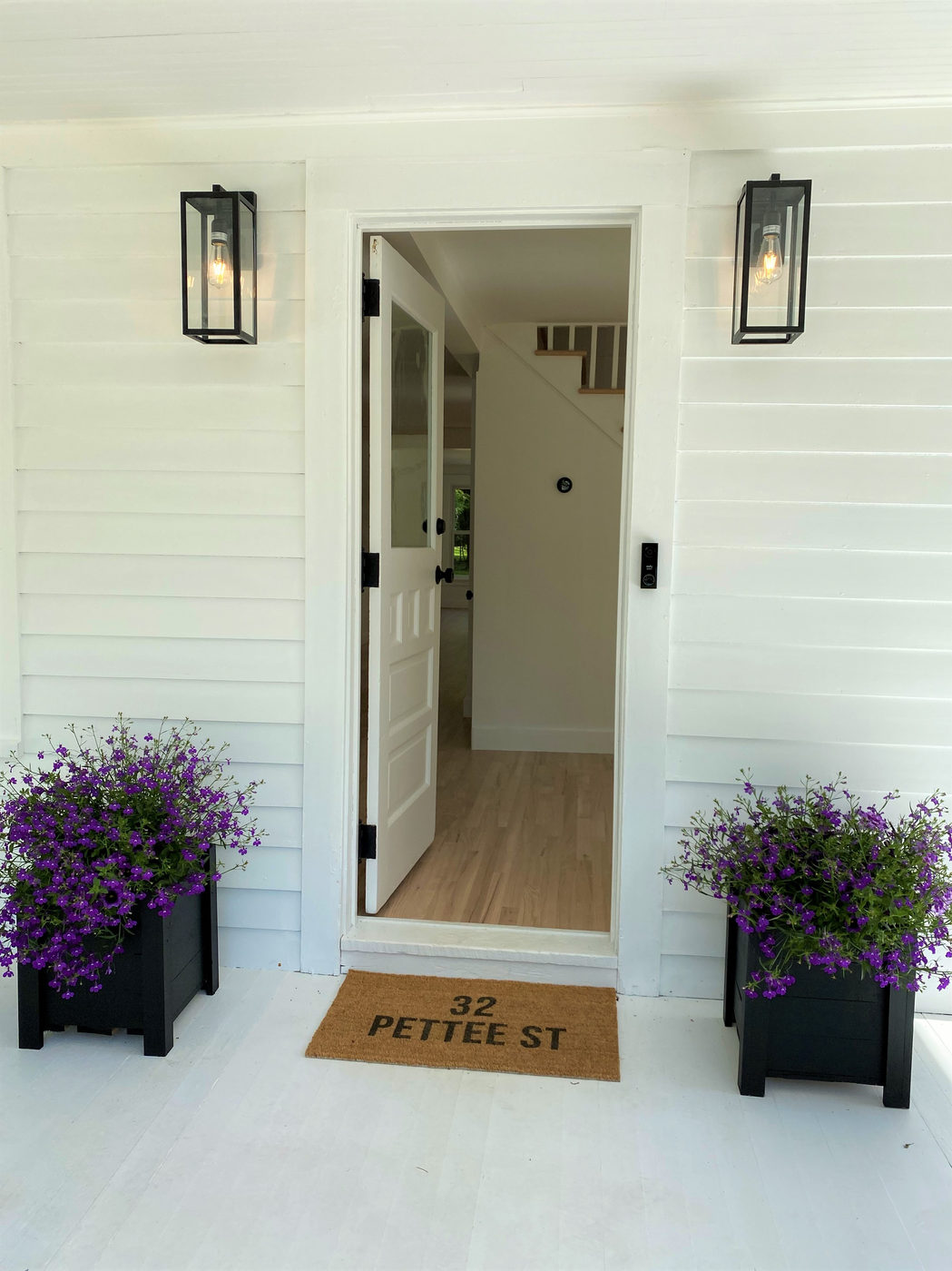 Front door flanked by black lanterns and lavender planters, 32 Pettee St doormat