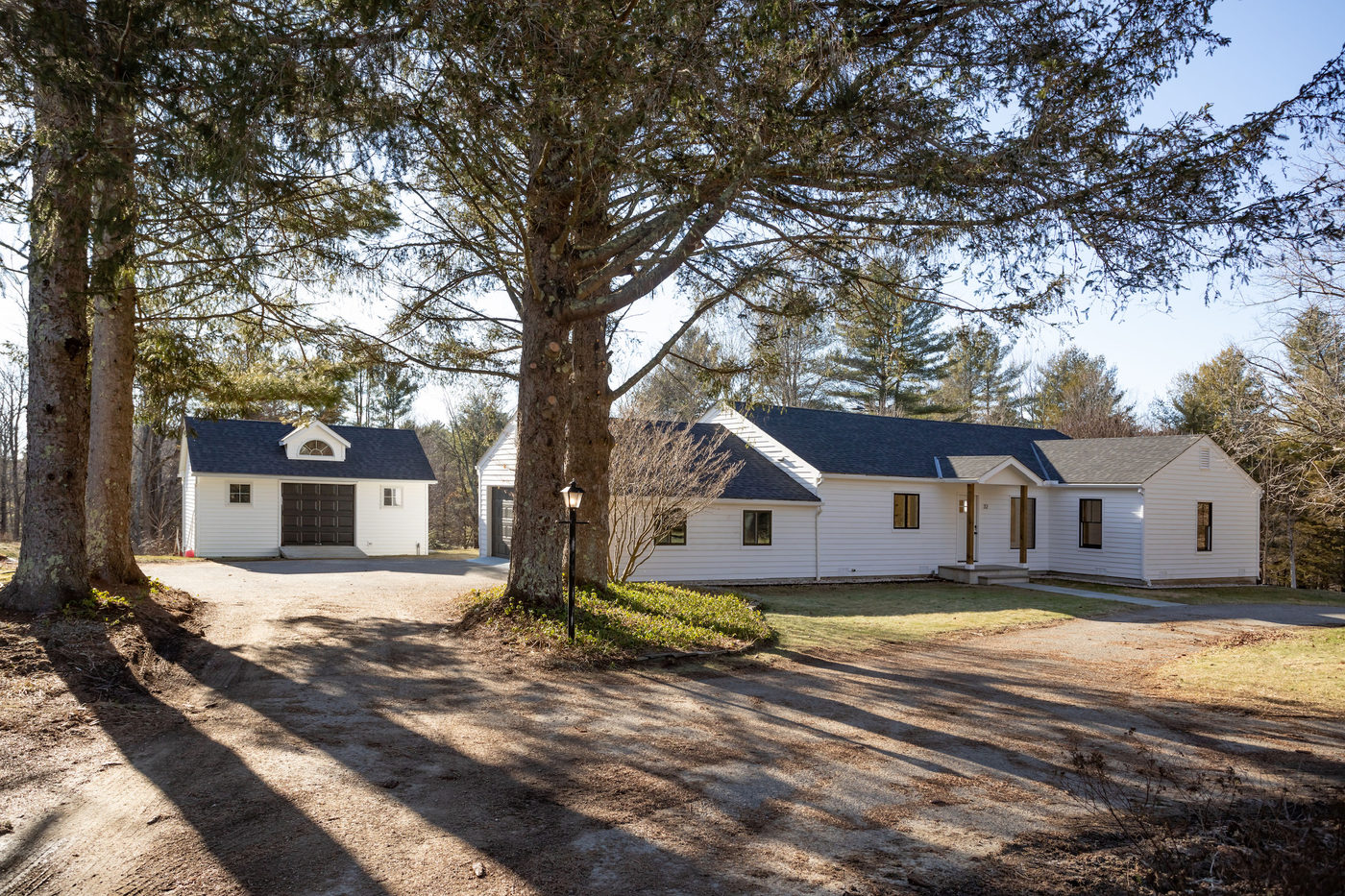 Long white ranch house set behind a curved lawn and mature plantings