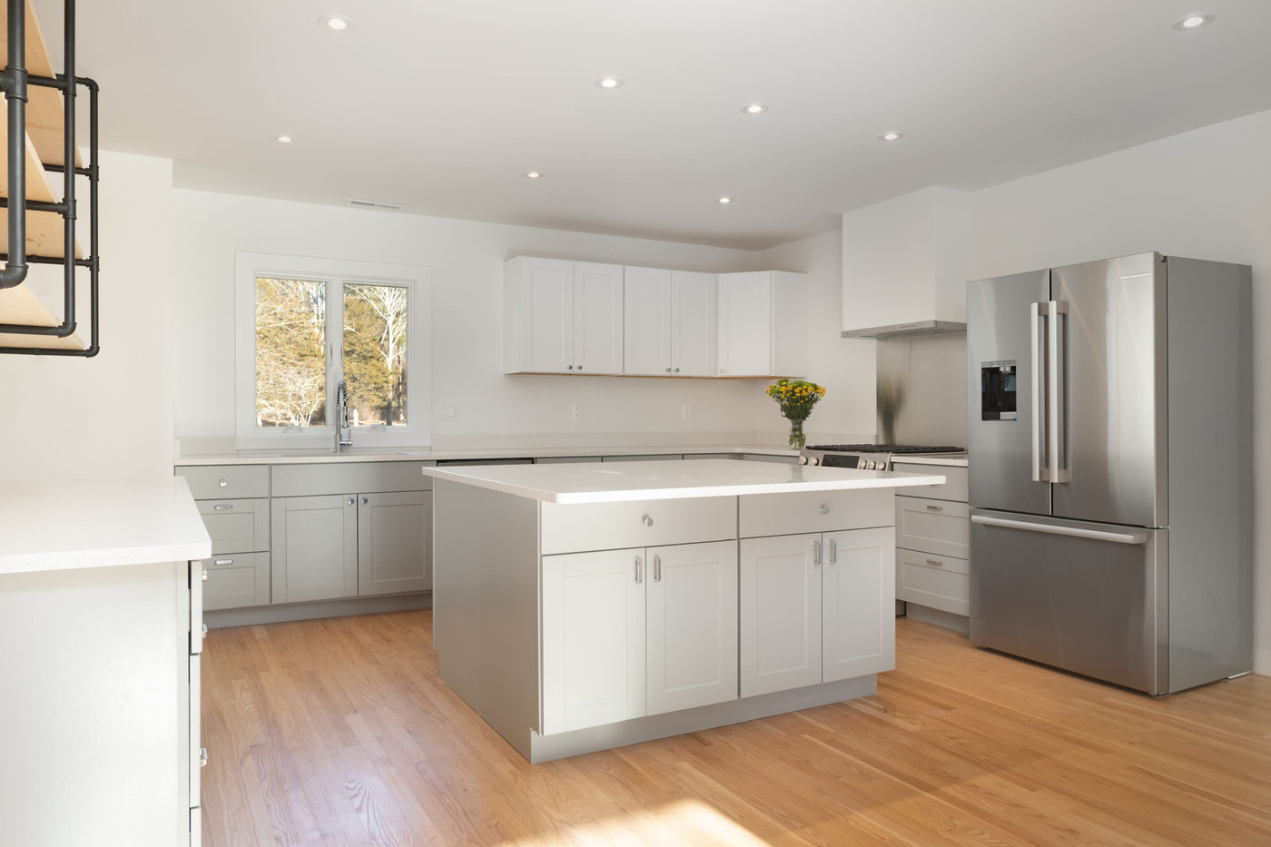Open white kitchen with a large island, marble counters and wood floors