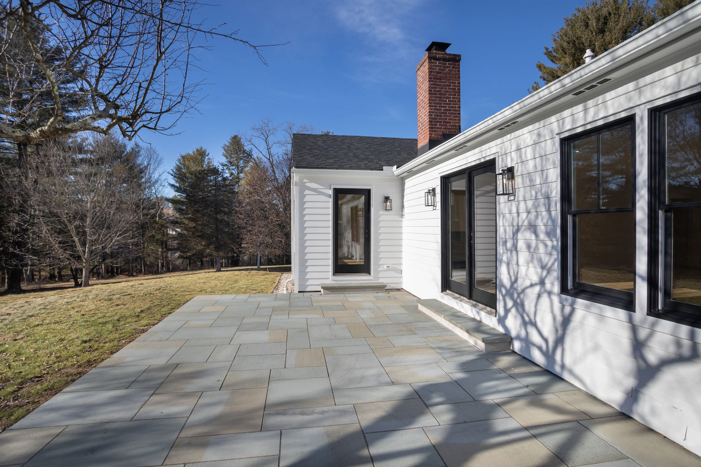 Bluestone patio beside the house with black-framed windows