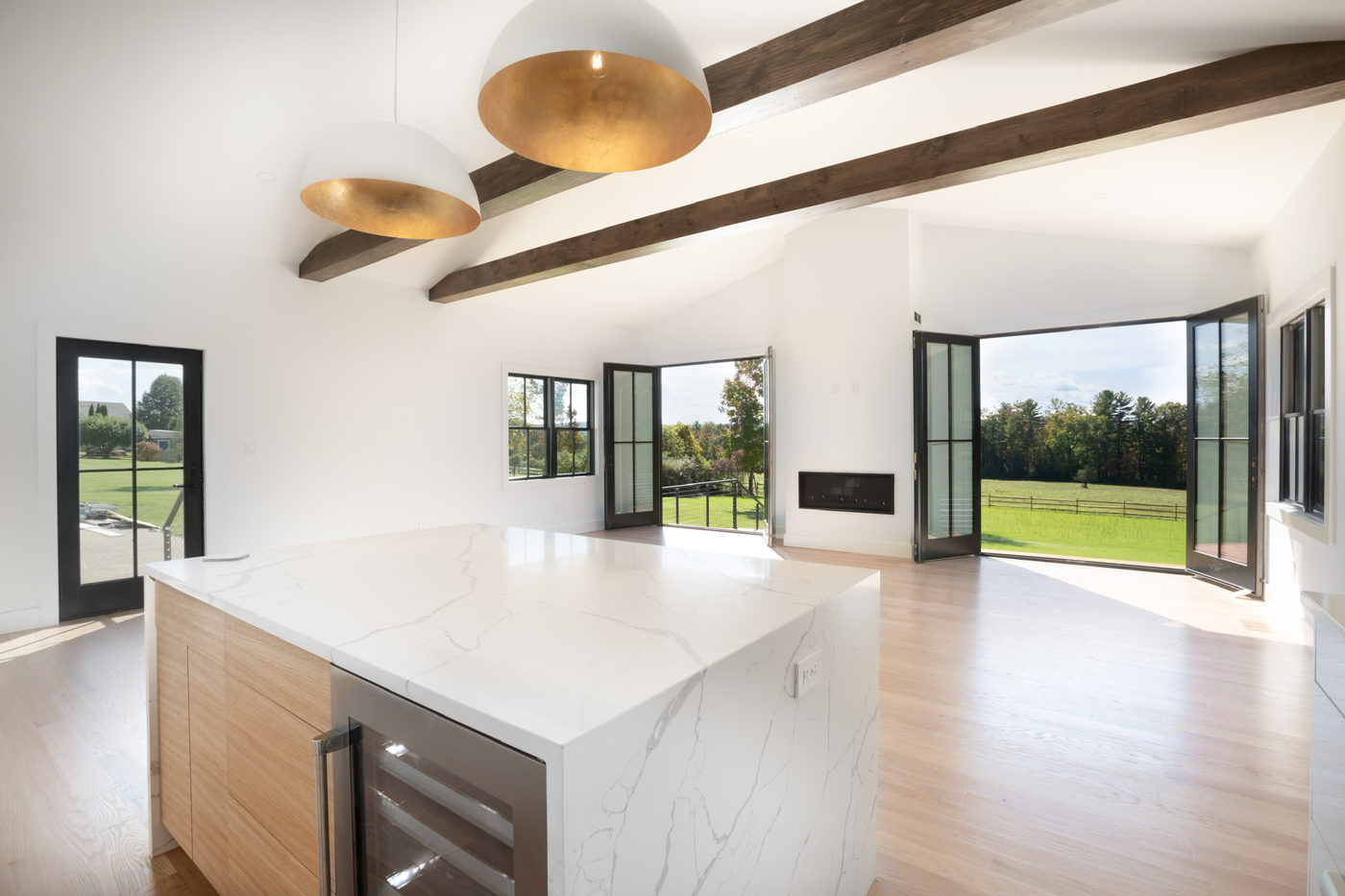 Double-height living space with dark exposed beams and a white oak kitchen island