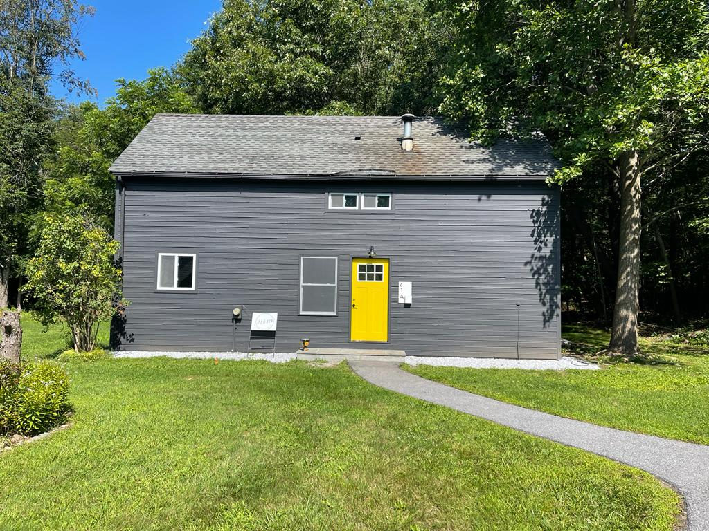 Grey two-storey house with a yellow front door and a mown lawn