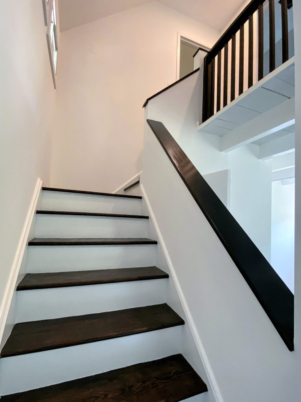 Stair with white risers, dark treads and a wood handrail