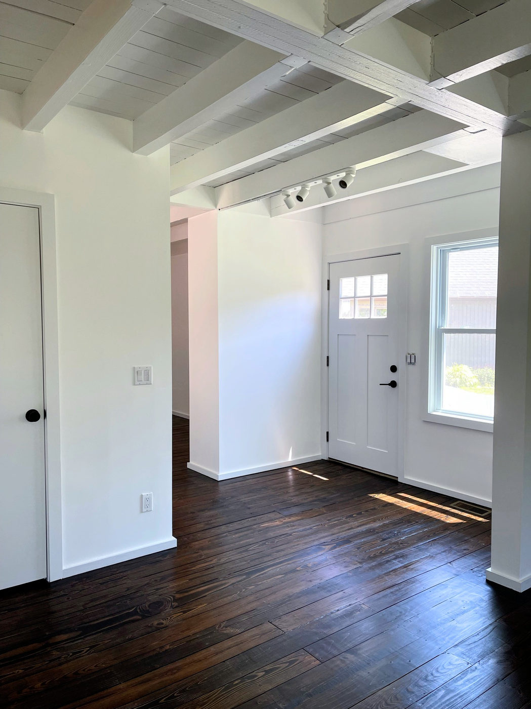 Entry hall with dark stained floors and a white panelled door