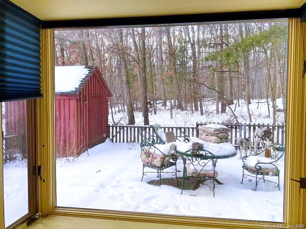 View through a window to a red barn and a snow-covered patio