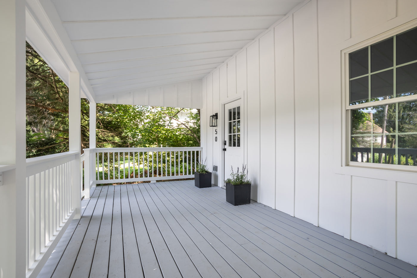 Deep covered porch with white railing and grey painted decking