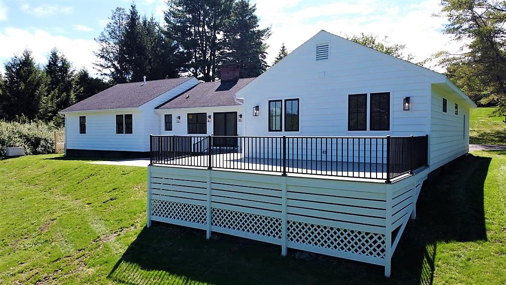 Long white house with a raised deck overlooking the lawn