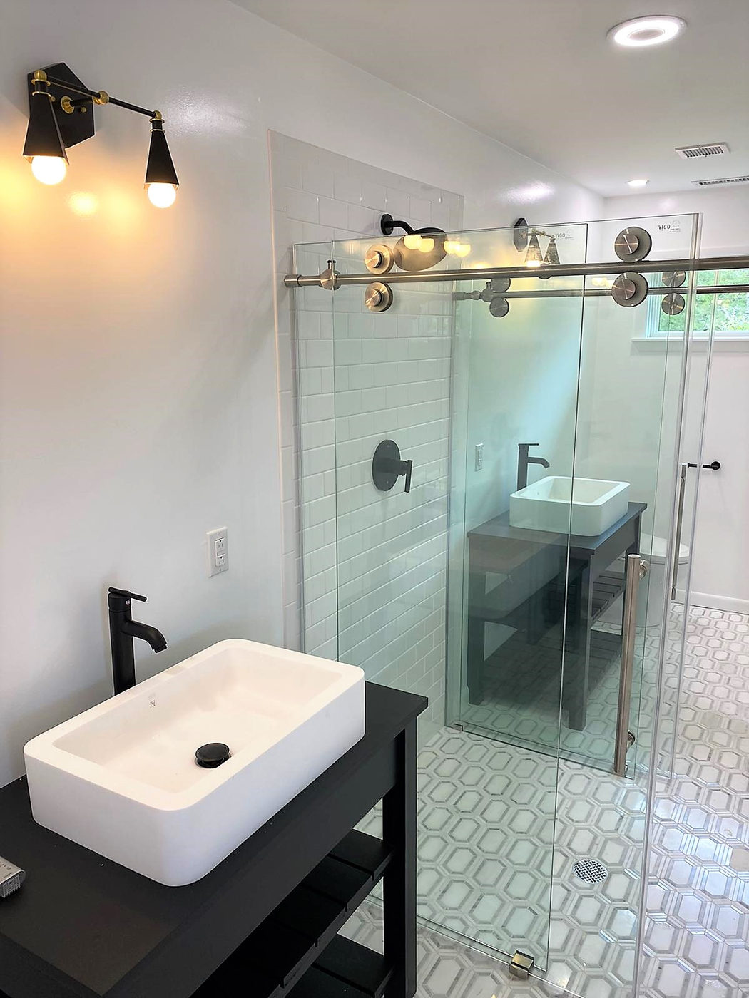 Bathroom with a vessel sink, black fixtures and a glass shower