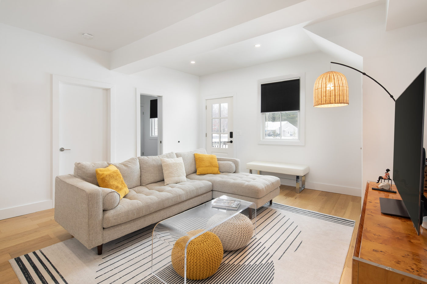 Apartment living room with a white sofa, oak floors and a wall-mounted television