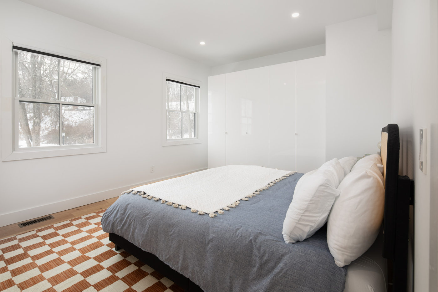 Bedroom with white and grey bedding and a chequered rug