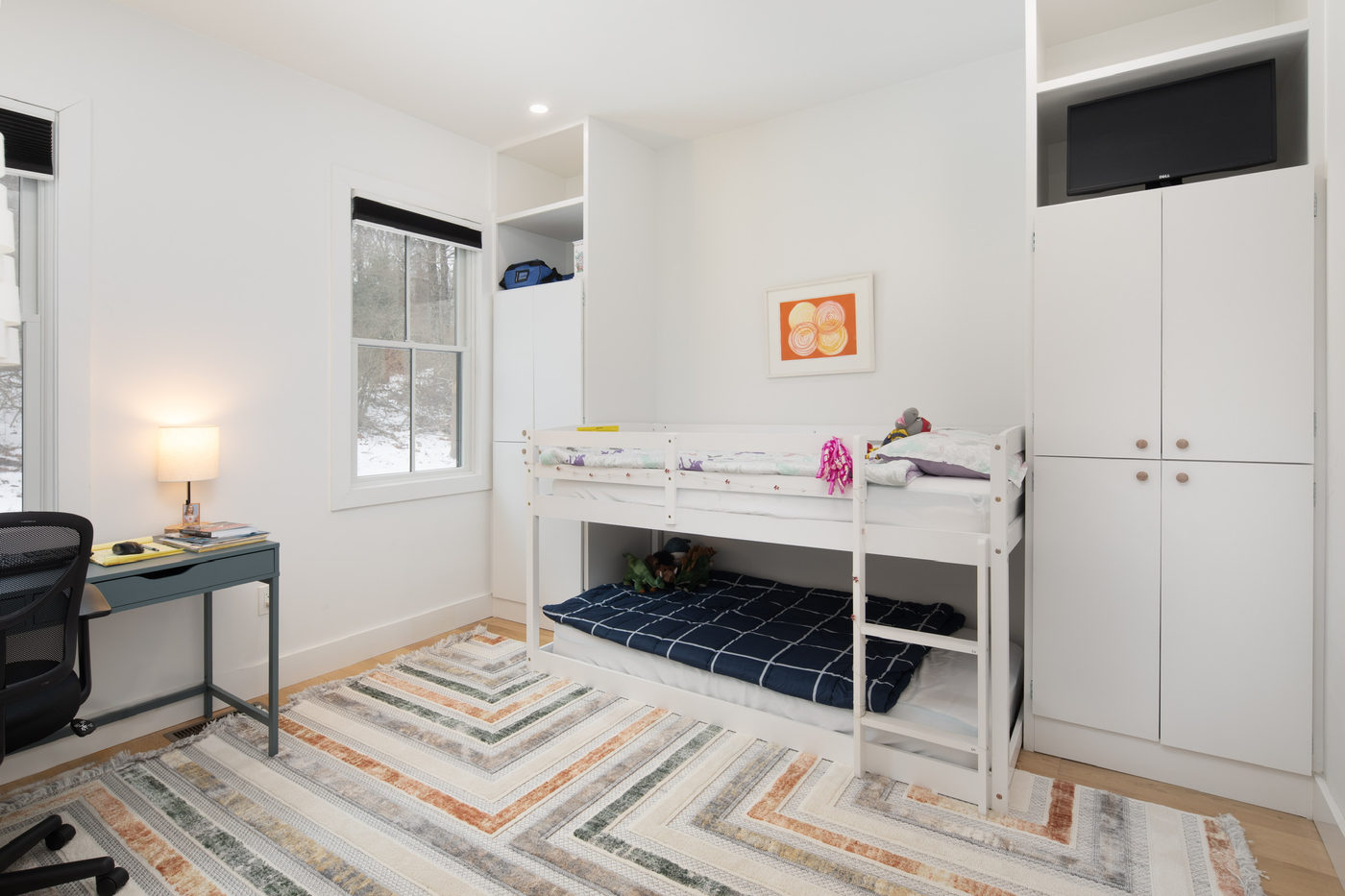 Room with bunk beds, a desk and a striped rug