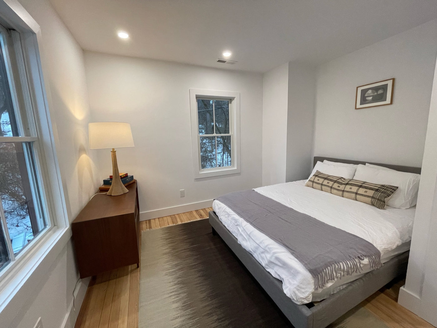 Bedroom with a large bed, wooden dresser and a table lamp